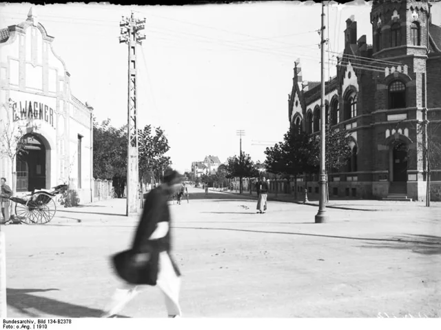 Street view with the corner studio building and a blurred pedestrian.