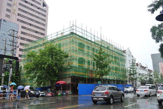 Street-corner former studio building behind scaffolding.